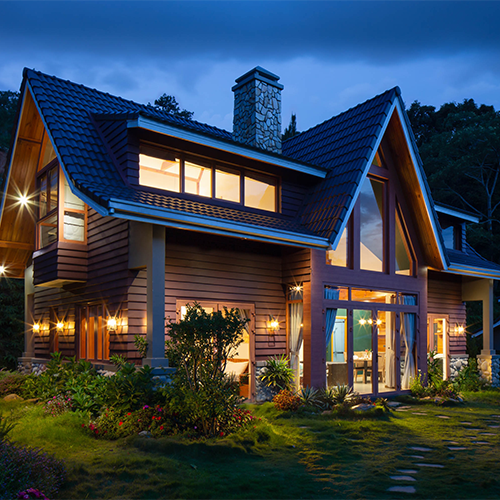 Belle maison éclairée dans les bois en début de soirée