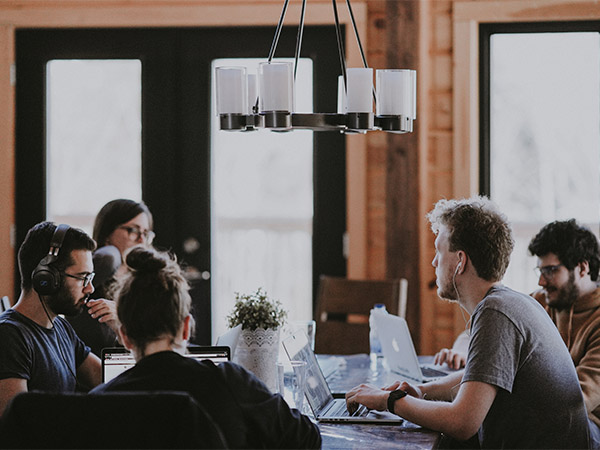 Des personnes hommes et femmes autour d'une table avec des ordinateurs en train de travailler.